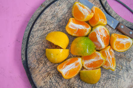 orange on a wooden board being sliced with a knifeの写真素材