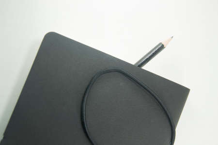 Black copybook with elastic band bookmark and pencilの写真素材