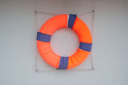 Red lifebuoy hanging on wall of a port building