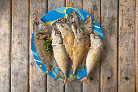 fried mackerel fish in blue dish on wood table
