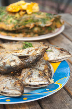 fried mackerel fish in blue dish on wood table