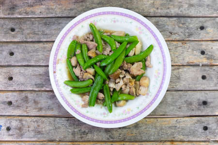 Stir fry green peas with pork on woodの写真素材