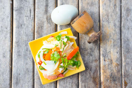 Spicy salad with salted eggs on yellow dishの写真素材
