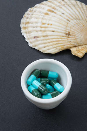 Jar with heap of blue green round capsule pills with medicine antibiotic
