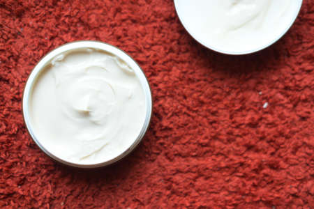 Hair wax and clay in tubs on red