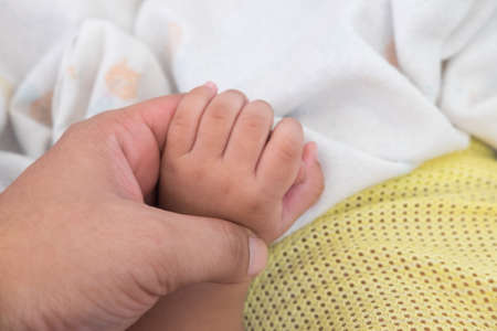 Close-up of baby's hand holding father's finger with tendernessの写真素材