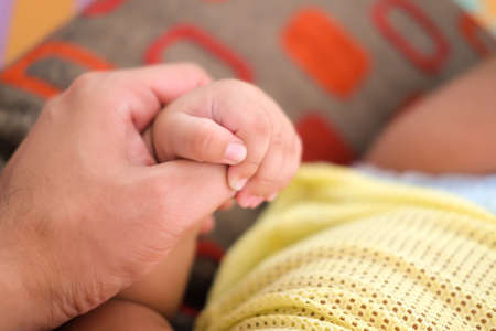 little son's hand holds daddy's big finger