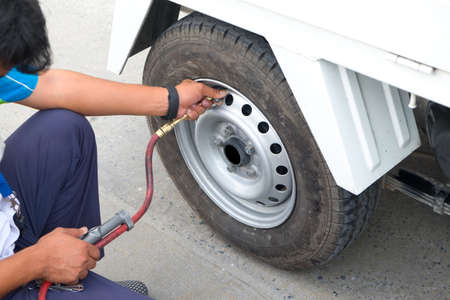 Man checking air pressure and filling air in the tires of his carの写真素材