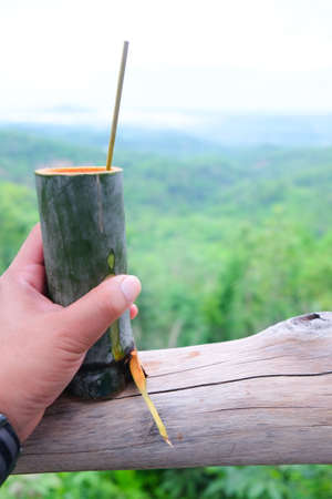 Bamboo cup with bamboo spoon in hand on nature backgroundの写真素材