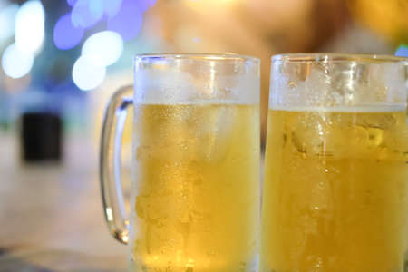 Two glass of beer against barrelsの写真素材