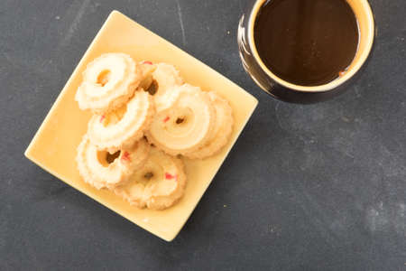 a cup of coffee and cookie on wood dish