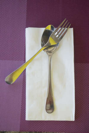spoon and fork with tissue on violet table