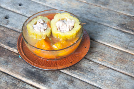 Stuffed bitter gourd with minced pork and carrot in clear soup on wood tableの写真素材