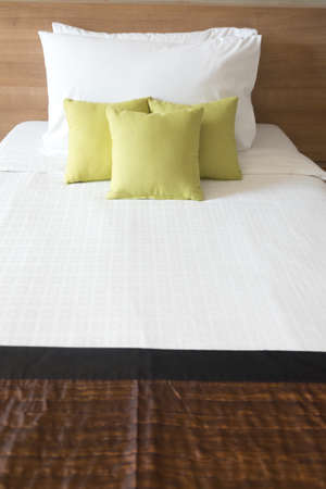 Green pillows on white bed in bedroomの写真素材
