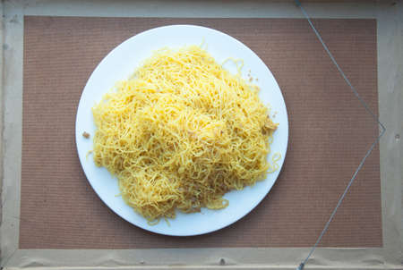 Egg noodles in white dish on a wooden table.