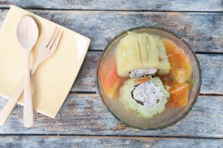 Stuffed bitter gourd with minced pork and carrot in clear soup on wood tableの写真素材