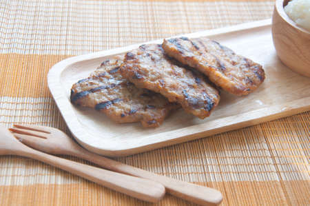 Thai food - grilled pork and sticky rice on wood plateの写真素材