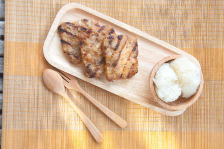 Thai food - grilled pork and sticky rice on wood plateの写真素材