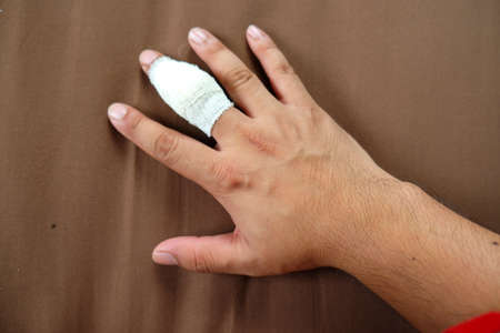 Finger injury with bandage on brown background