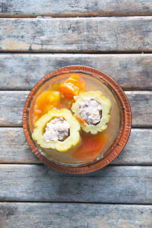 Stuffed bitter gourd with minced pork and carrot in clear soup on wood table
