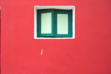 green wood window on a pink wall. Window with closed, green window in the wall of the house.の写真素材