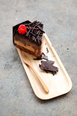 cherries topping from slice of chocolate cake on wood table.の写真素材