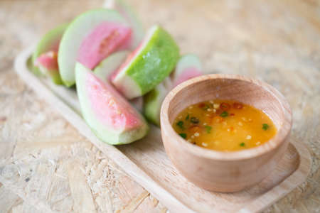 Ripe guava fruit cut with sweet sauce, Thai food on wood tray. Selective focusの写真素材