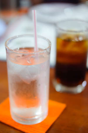 glass of water with a straw on wood tableの写真素材