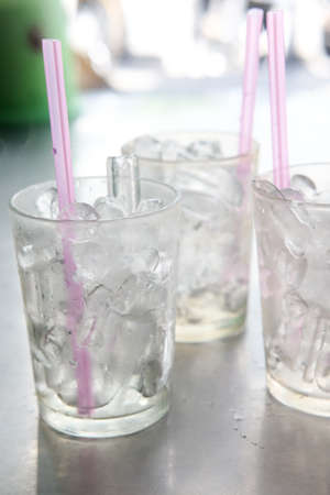 Ice in glass with straw on table
