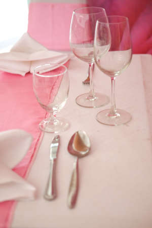 Dining table with wine glasses and pink tablecloth ready for guests