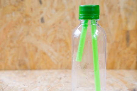 Green straws inside a transparent bottle wood backgroundの写真素材