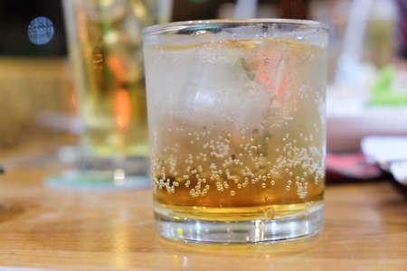Glass of whiskey with ice on tableの写真素材