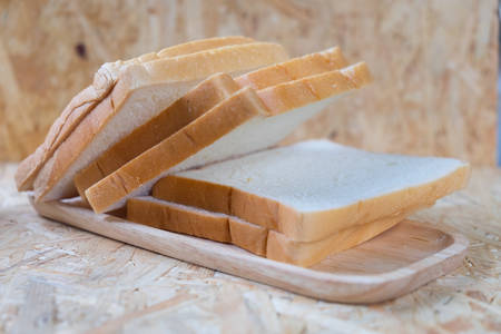 Tasty bread slices on wood trayの写真素材
