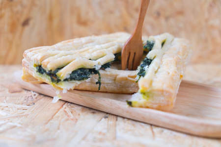 spinach pie on wood tray, eating pieの写真素材