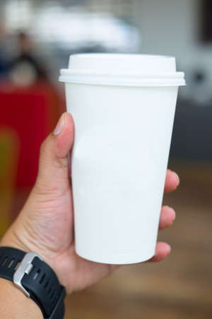 man's hand holding white empty paper coffee cup with a  plastic capの写真素材