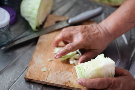 Senior women hands cutting cabbage for salad. cooking and home conceptの写真素材