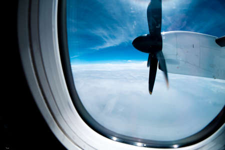 engine and propeller of the plane, view from window airplane, white clouds and blue sky as backgroundの写真素材