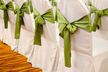 Chairs for a party with green covers ribbon and bowの写真素材