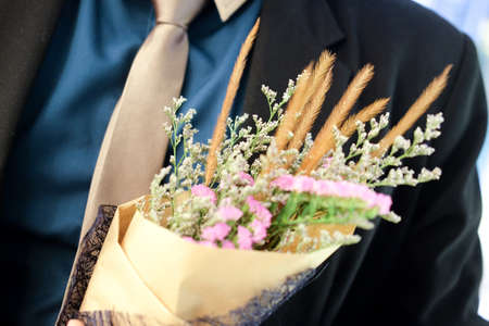 Young man in fashionable suit holding hipster hand-made bouquet.の写真素材