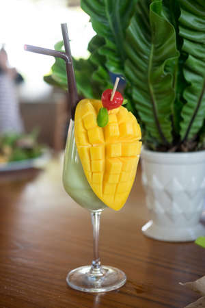 Fresh tropical fruit smoothie mango juice and fresh mango on wood tableの写真素材