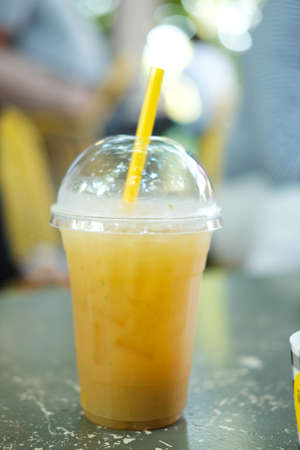 Cocktail with fruit juice and ice cubes in takeaway glassの写真素材