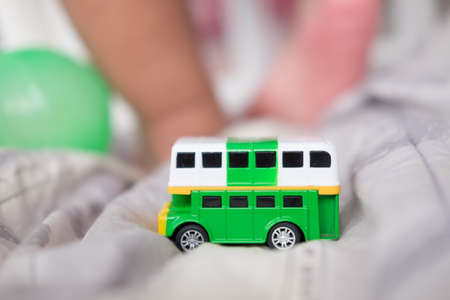 green double decker bus toys with baby foot backgroundの写真素材