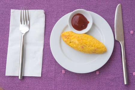 Hot omelet with tomato sauce in white dish on the table for breakfast