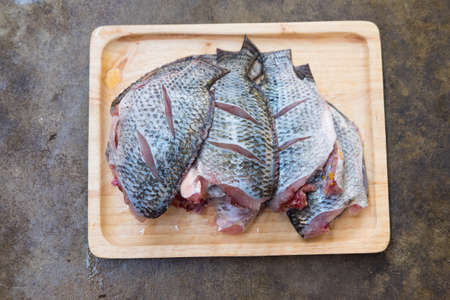 Raw Tilapia fish on wooden tray ready to fish fryの写真素材