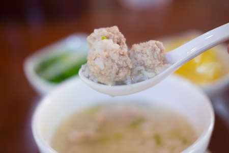 Close up minced pork on white spoon soft boiled rice, Thai style breakfast with pork