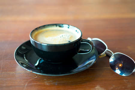 Hot coffee in black cup with sunglasses on tableの写真素材