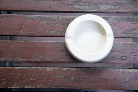 White ceramic ashtray on a wooden backgroundの写真素材