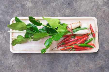 Thai Tom Yam soup herbs and spices lemongrass kaffir lime leaves galangal and chilli in tray woodの写真素材