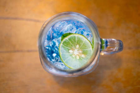 Blue cocktail refreshing summer drink with lime  and ice on wooden tableの写真素材
