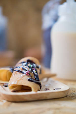 roll pancake filling with cream and topping with chocolate sauceの写真素材